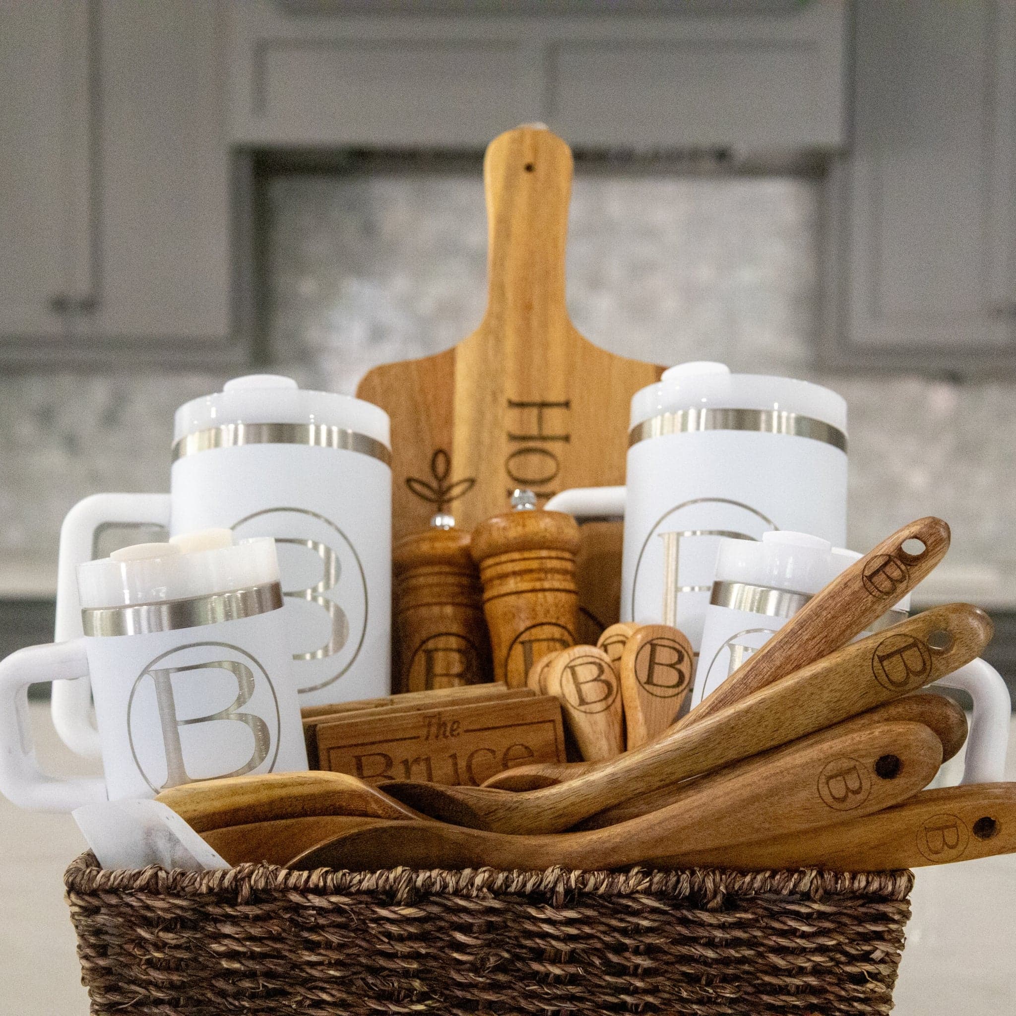 A gift basket with monogrammed tumblers, an engraved cutting board, and personalized utensils, all reading 'The Bruce Family'